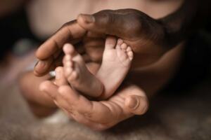postpartum mother holding her newborn baby's feet